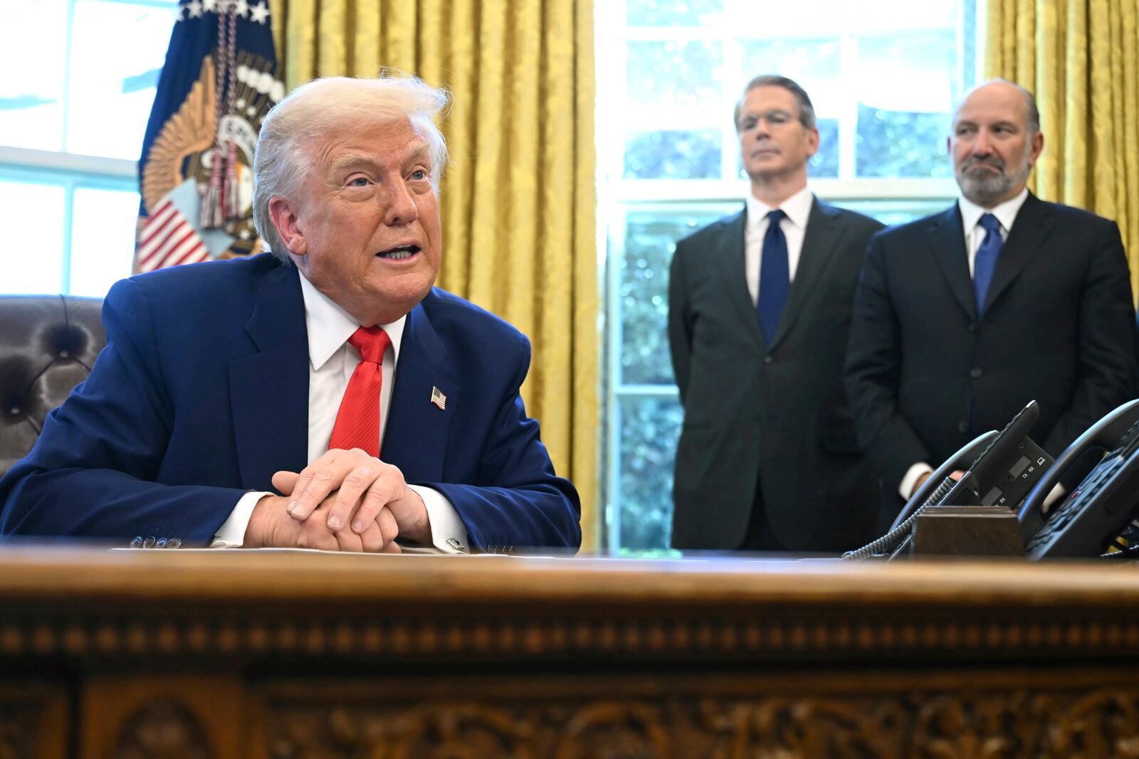 President Donald Trump speaks after signing an executive order in the Oval Office of the White House Wednesday, April 9, 2025, in Washington, as Treasury Secretary Scott Bessent and Commerce Secretary Howard Lutnick listen. (Pool via AP)