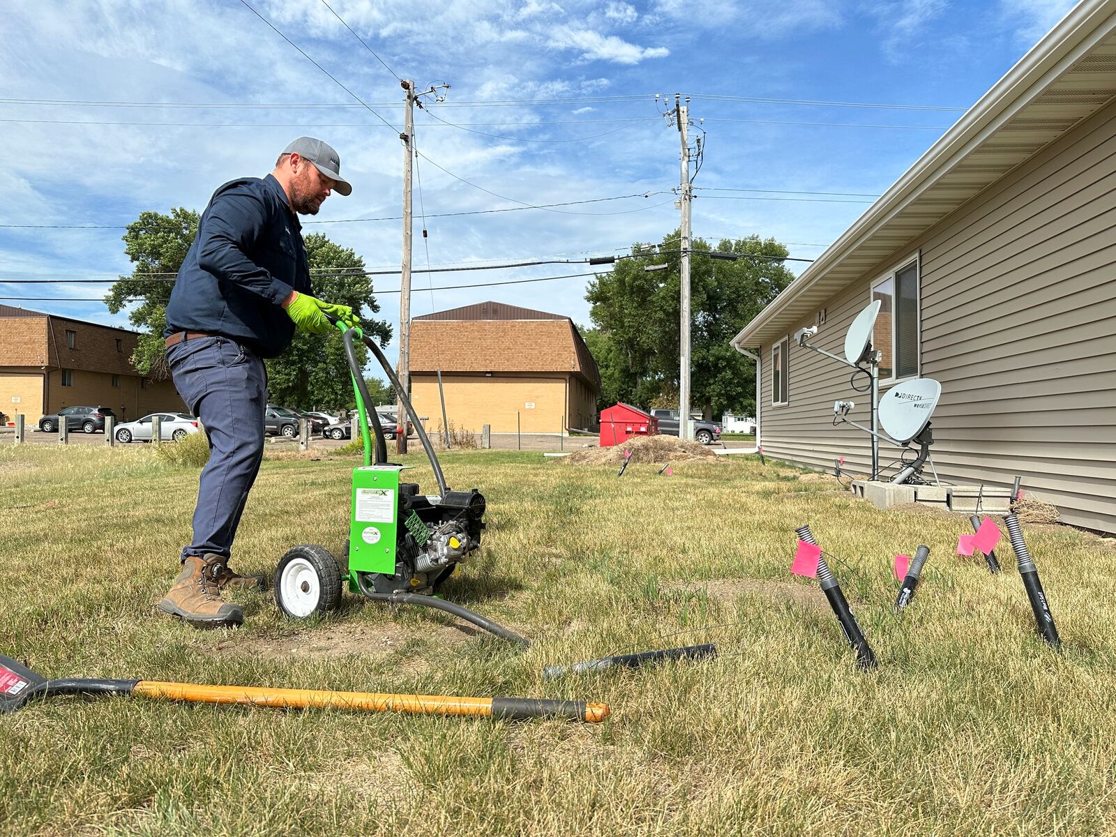Joshua Herman pumps carbon monoxide into burrows dug by Richardson's ground squirrels along an apartment building on Monday, July 14, 2025, in Minot, N.D. (AP Photo/Jack Dura)