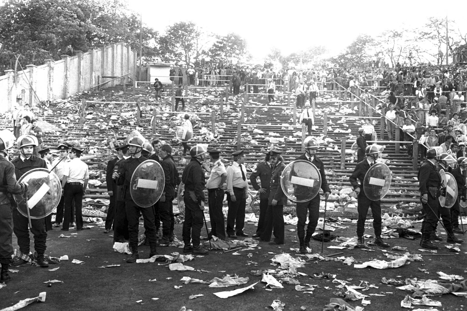 FILE - Belgian riot policemen stand with other police in a line in front of a totally littered stand after various fan groups rioted, in the Heysel Stadium in Brussels, Belgium, Wednesday, May 29, 1985. (AP Photo, File)