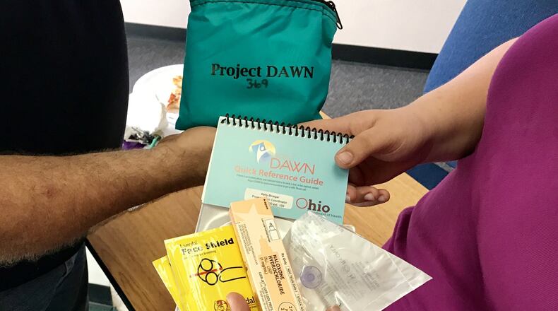 A family examines the inside of a Narcan kit at the Conversation for Change program in Springfield. STAFF PHOTO/MICHAEL COOPER