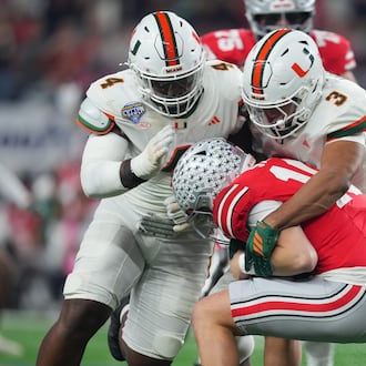 Ohio State quarterback Julian Sayin, center, is sacked by Miami defensive lineman Rueben Bain Jr., left, and defensive lineman Akheem Mesidor during the first half of the Cotton Bowl College Football Playoff quarterfinal game Wednesday, Dec. 31, 2025, in Arlington, Texas. (AP Photo/Julio Cortez)