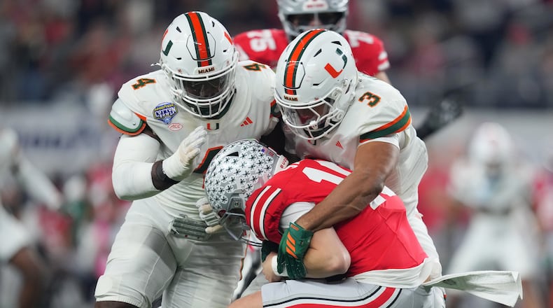 Ohio State quarterback Julian Sayin, center, is sacked by Miami defensive lineman Rueben Bain Jr., left, and defensive lineman Akheem Mesidor during the first half of the Cotton Bowl College Football Playoff quarterfinal game Wednesday, Dec. 31, 2025, in Arlington, Texas. (AP Photo/Julio Cortez)