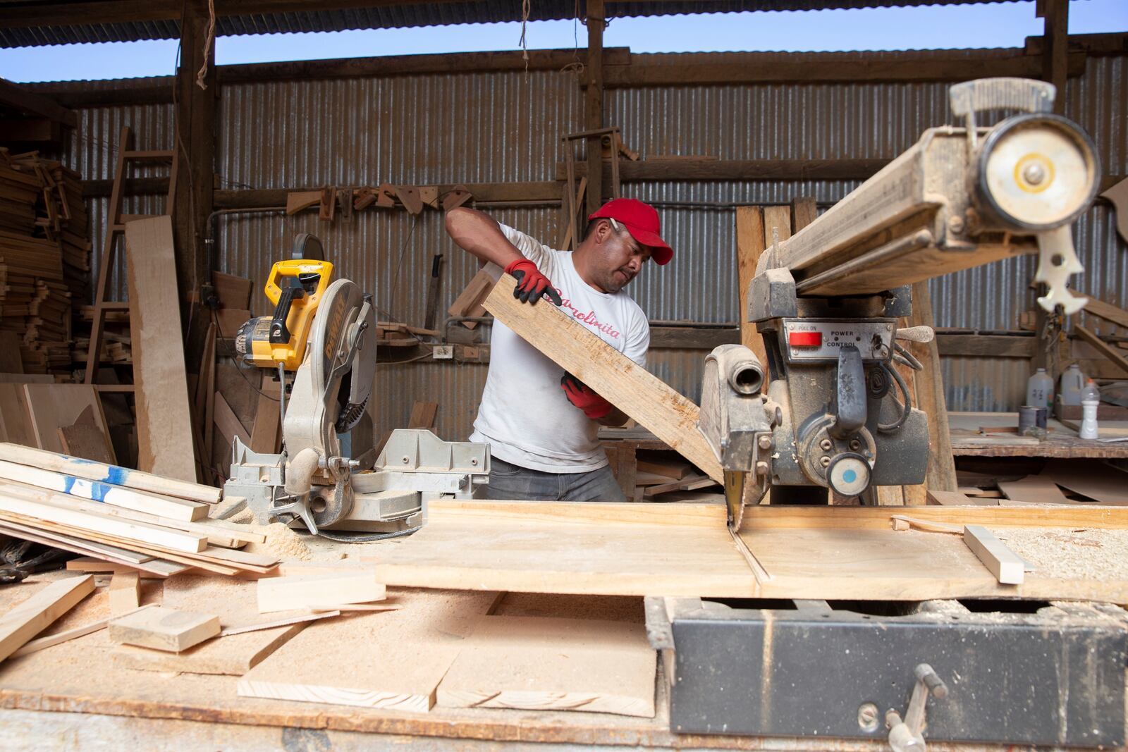 Ex-migrant Eduardo Jimenez saws wood in a carpentry workshop in Cajola, Guatemala, Nov. 29, 2021. Jimenez’s project creates doors and woodwork for homes paid for with money sent home from the U.S. (AP Photo/Megan Janetsky)