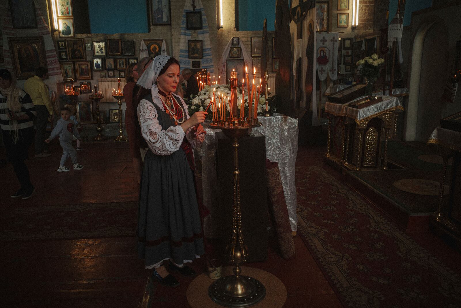 A woman lights a candle during the celebration of Orthodox Easter at St. John Theologian Church of the Orthodox Church of Ukraine in Kharkiv, Ukraine, on Sunday, April 20, 2025. (AP Photo/George Ivanchenko)