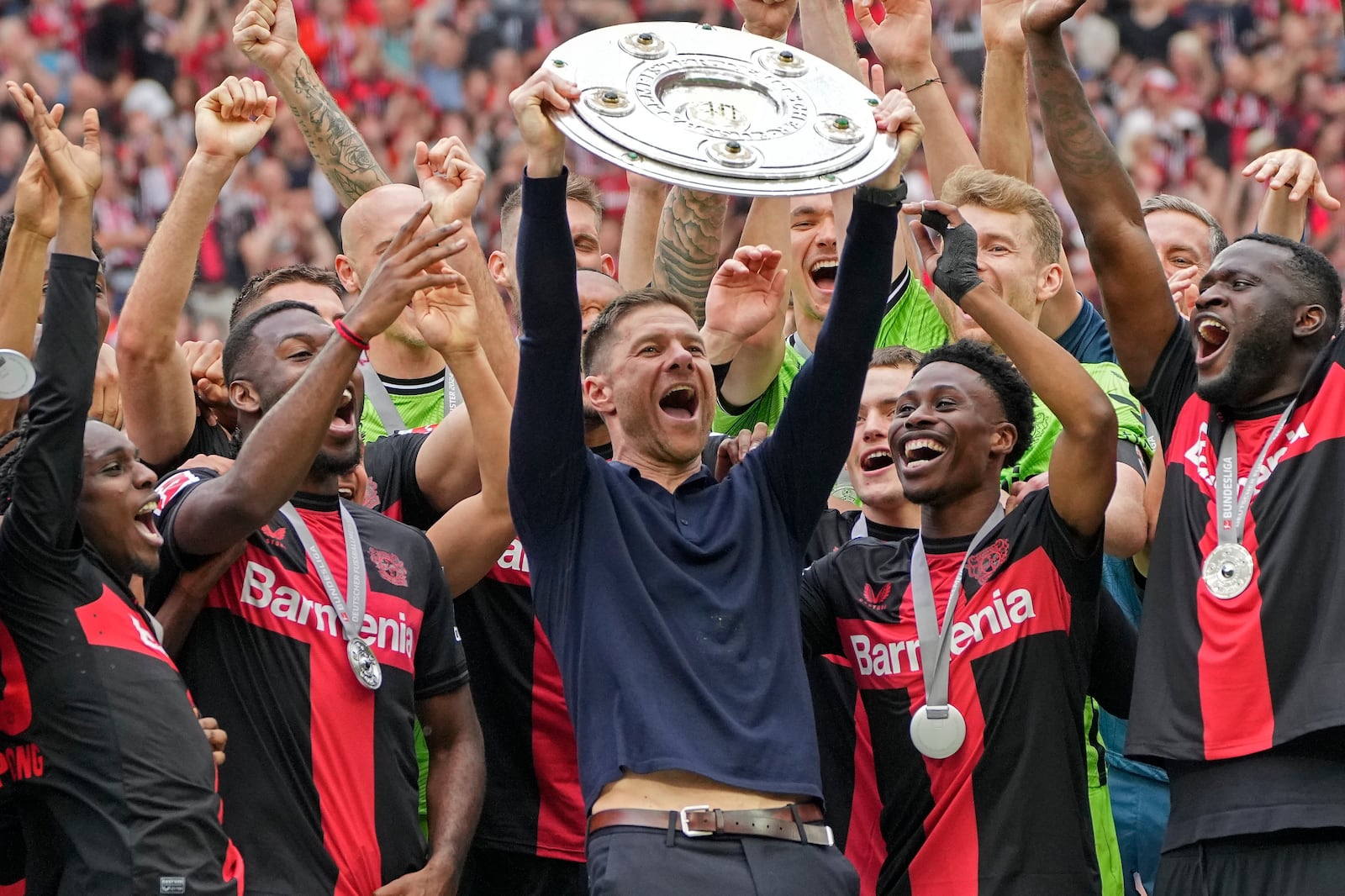 FILE - Leverkusen's head coach Xabi Alonso celebrates with the trophy as his team won the German Bundesliga, after the German Bundesliga soccer match between Bayer Leverkusen and FC Augsburg at the BayArena in Leverkusen, Germany, Saturday, May 18, 2024. (AP Photo/Martin Meissner, File)