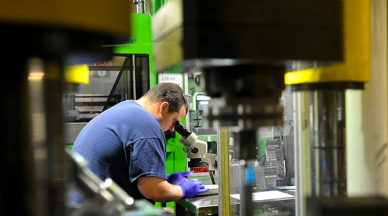 Ultra-Met employee Justin Fraley uses a microscope to check the products he’s producing for flaws Friday at the company’s Urbana manufacturing facility. Staff photo by Bill Lackey