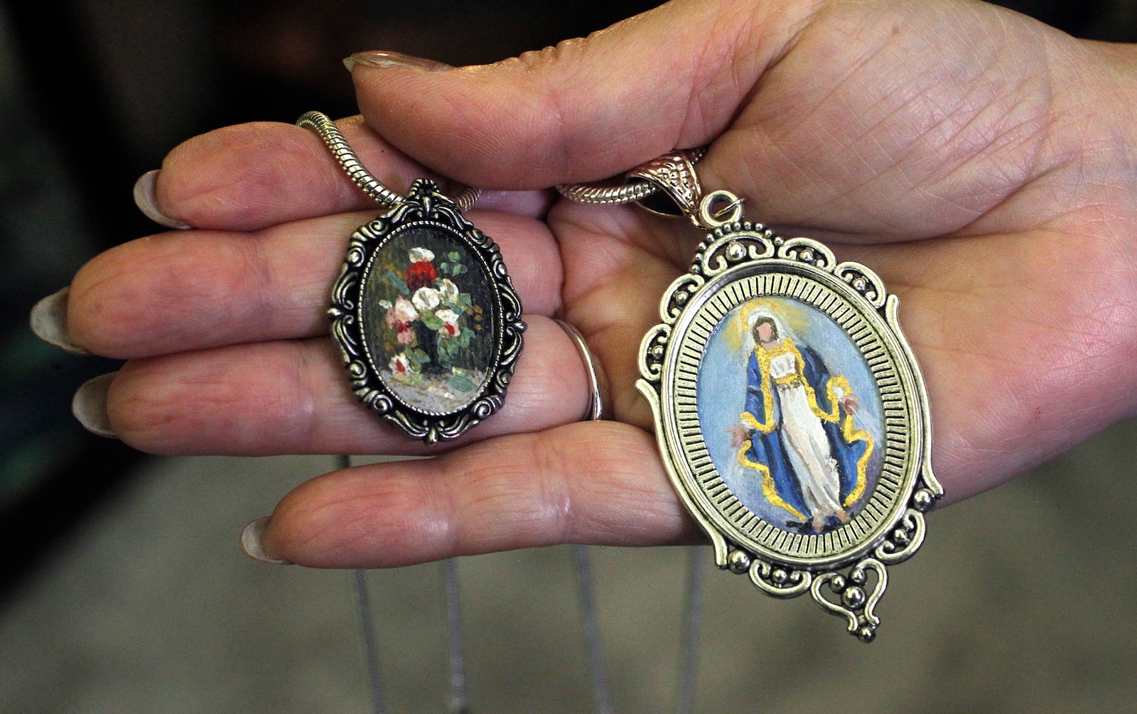 Centerville artist Cecilia Brendel's mini masterpieces come in one and two-inch ovals framed in a pendant.  LISA POWELL / STAFF