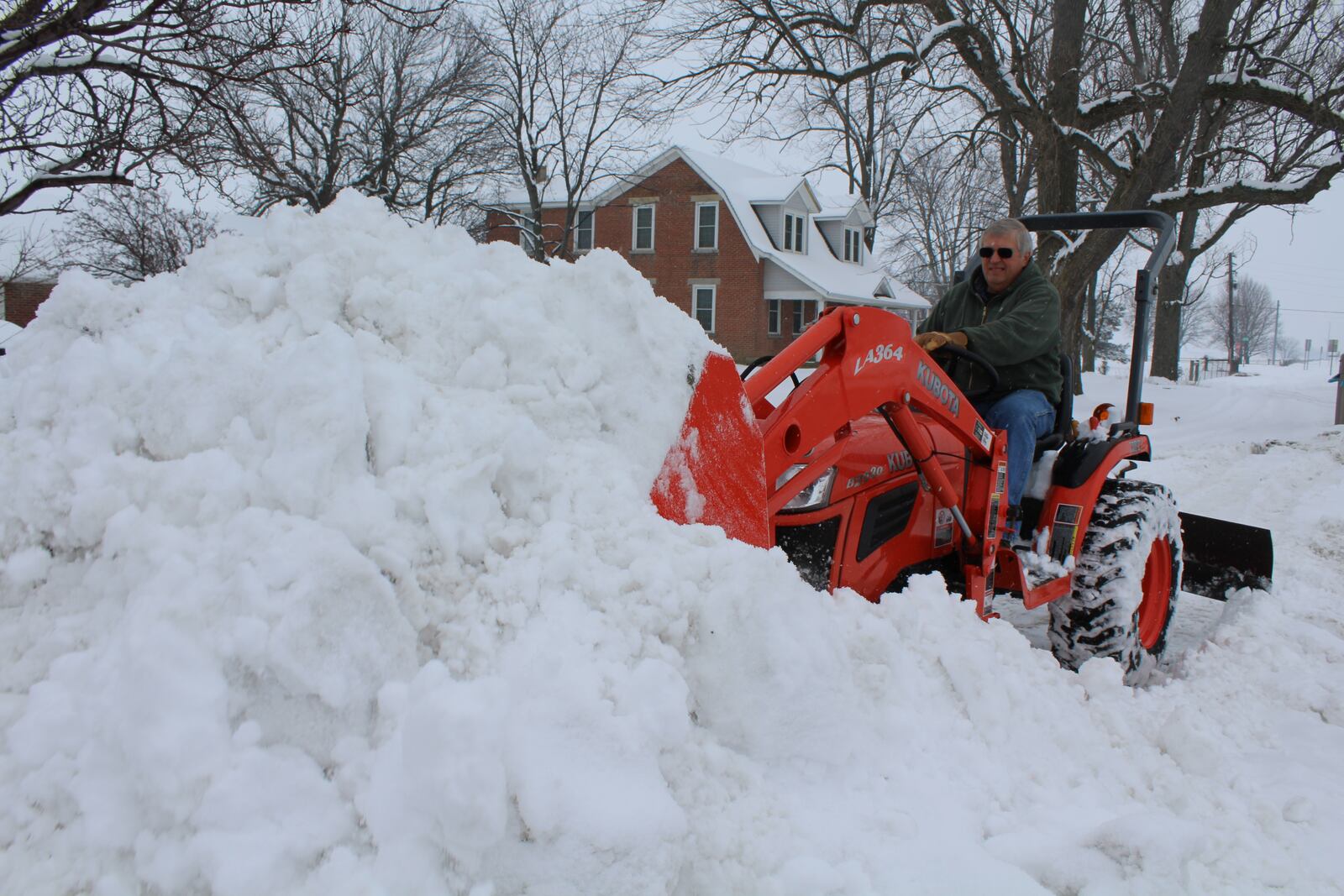 Randy Lambright moves snow that he describes as "wet and heavy" on his property along Ohio 49 in Arcanum. DEE MOORMAN / STAFF