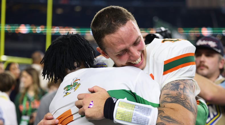 Miami quarterback Carson Beck, right, is hugged by former NFL player Michael Irvin following the Cotton Bowl College Football Playoff quarterfinal game against Ohio State Wednesday, Dec. 31, 2025, in Arlington, Texas. (AP Photo/Gareth Patterson)