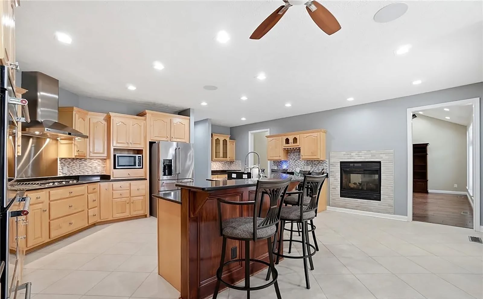 The eat in kitchen has tile flooring, recessed lighting, a ceiling fan and an island with bar seating. There is a planning desk, a wine and a coffee bar and a see through fireplace as well as exterior doors opening to the back deck. CONTRIBUTED