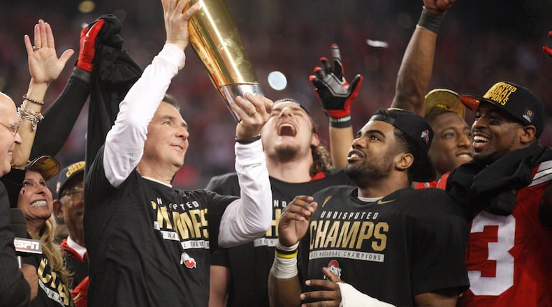 Ohio State's Urban Meyer hoists the trophy as Joey Bosa, Ezekiel Elliott and Tyvis Powell watch hafter beating Oregon in the national championship game on Monday, Jan. 12, 2015, at AT&T Stadium in Arlington, Texas.