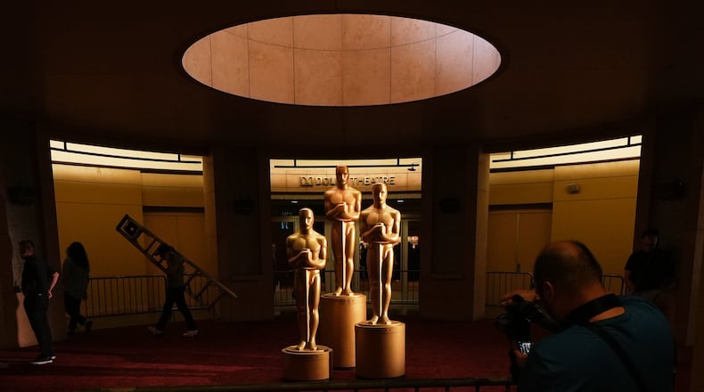 People look on as workers install Oscar statues Saturday, March 14, 2026, at the Dolby Theatre in Los Angeles, in preparation for Sunday's 98th Academy Awards ceremony. (AP Photo/Gregory Bull)