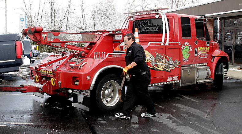 Hollis Shifflett, the owner of Hollis Towing, hooks up a vehicle to his tow truck in Miamisburg last month. Ohio’s tow truck operators will be rolling under a lengthy set of new regulations in 2015, rules aimed at giving owners of towed vehicles more rights. Among other consumer protections, the legislation requires towing firms to let vehicle owners remove personal property from their vehicles without charge. It also requires truck operators to tell owners who arrive at the scene during the hook up that they can pay half a tow charge to have the vehicle released. Tow truck drivers would have to take photos to show a vehicle was in violation. LISA POWELL / STAFF PHOTO