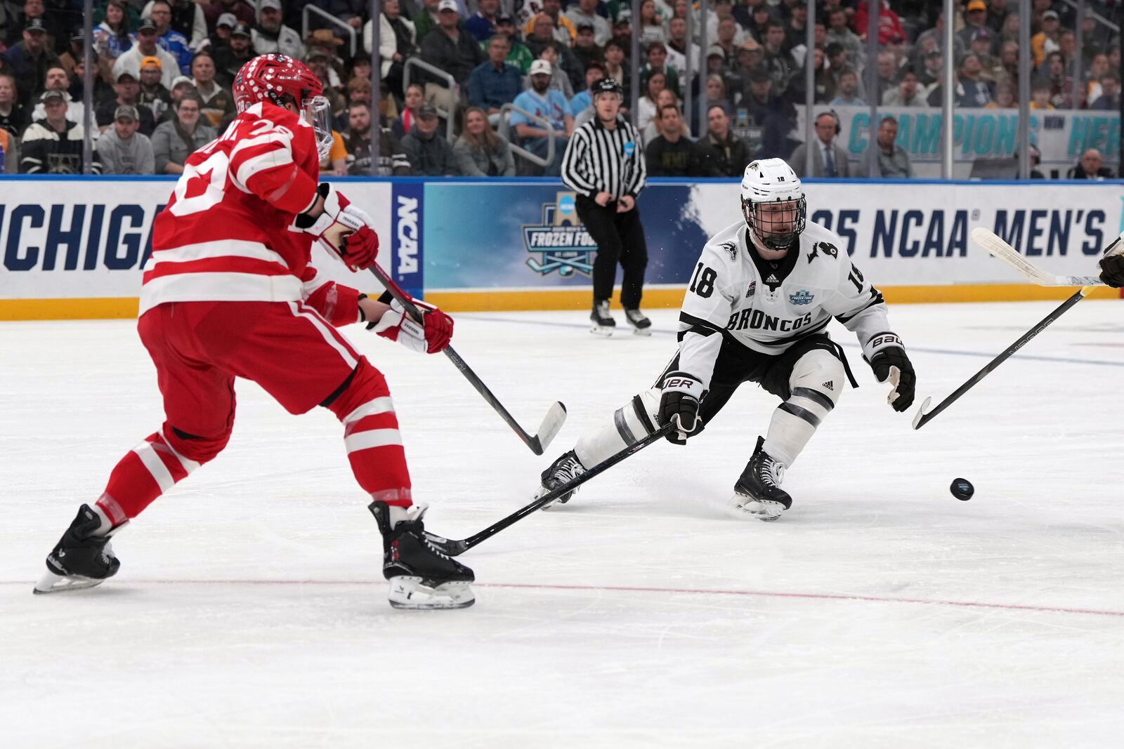 Boston University's Sascha Boumedienne, left, pass around Western Michigan's Wyatt Schingoethe (18) during the first period in the championship game of the NCAA Frozen Four men's college hockey tournament, Saturday, April 12, 2025, in St. Louis (AP Photo/Jeff Roberson)