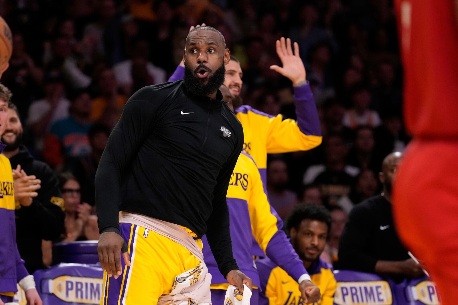 Los Angeles Lakers forward LeBron James, left, celebrates from the bench after the Lakers scored during the second half of an NBA basketball game against the Houston Rockets Friday, April 11, 2025, in Los Angeles. (AP Photo/Mark J. Terrill)