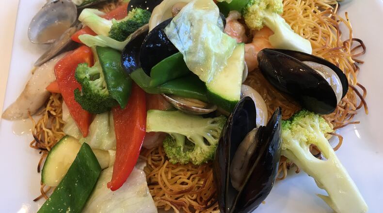 A pan-fried noodle cake topped with fresh cooked vegetables and seafood ($15) including a generous number of shrimps, scallops, mussels and clams served at Sugar & Spice Asian Bistro on Brown Street. Contributed photo by Alexis Larsen