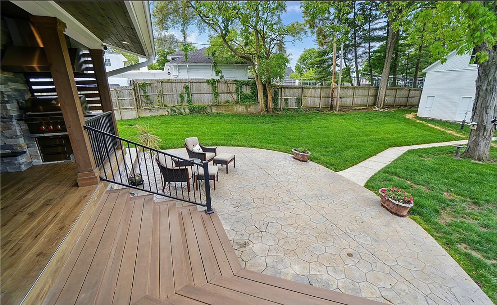 The back of the home features an updated covered deck with outdoor kitchen. The original carriage house has a concrete walkway leading from patio.