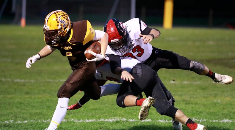 Kenton Ridge’s Zach Schneider gets knocked out of bounds by Tecumseh s Ryan Rowland and Caleb Edwards as he carries the ball. Bill Lackey/Staff