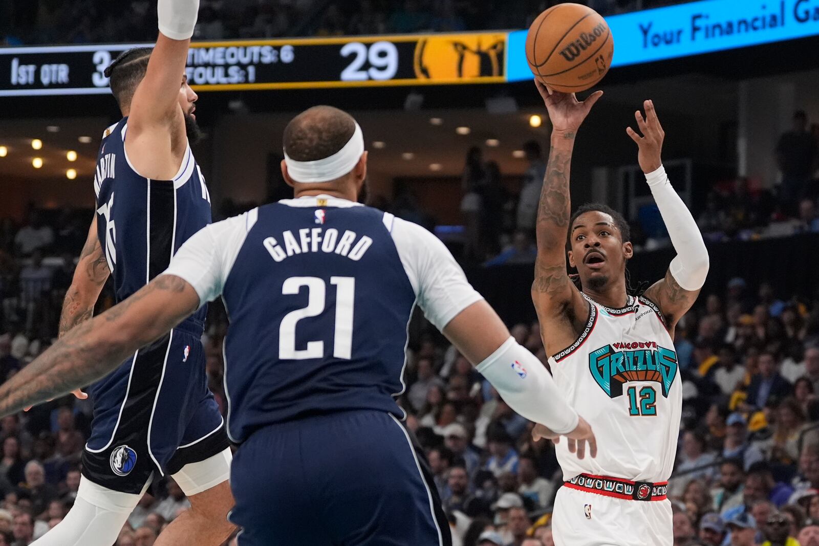 Memphis Grizzlies guard Ja Morant (12) shoots the ball past Dallas Mavericks forward Caleb Martin (16) and center Daniel Gafford (21) during the first half of an NBA play-in tournament basketball game Friday, April 18, 2025, in Memphis, Tenn. (AP Photo/George Walker IV)