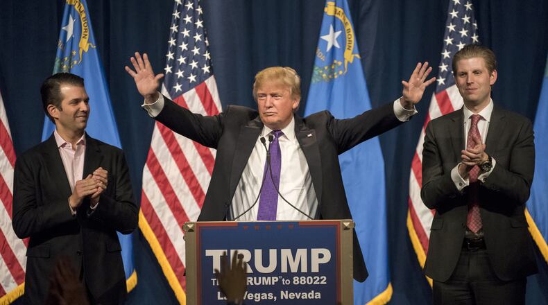 Donald Trump Jr., left, and Eric Trump, right, applaud their father during a caucus night rally in Las Vegas on Feb. 23, 2016.