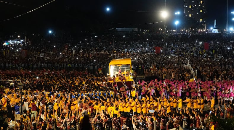Catholic devotees walk beside a glass-covered carriage carrying the image of Jesus Nazareno during its annual procession in Manila, Philippines, on its feast day, Friday Jan. 9, 2026. (AP Photo/Aaron Favila)