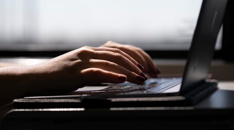 FILE - A woman types on a laptop while on a train in New Jersey, May 18, 2021. A trial of a four-day workweek in Britain, billed as the world's largest, has found that an overwhelming majority of the 61 companies that participated over six months last year will keep going with the shorter hours and that most employees were less stressed and burned out and had better work-life balance. (AP Photo/Jenny Kane, File)