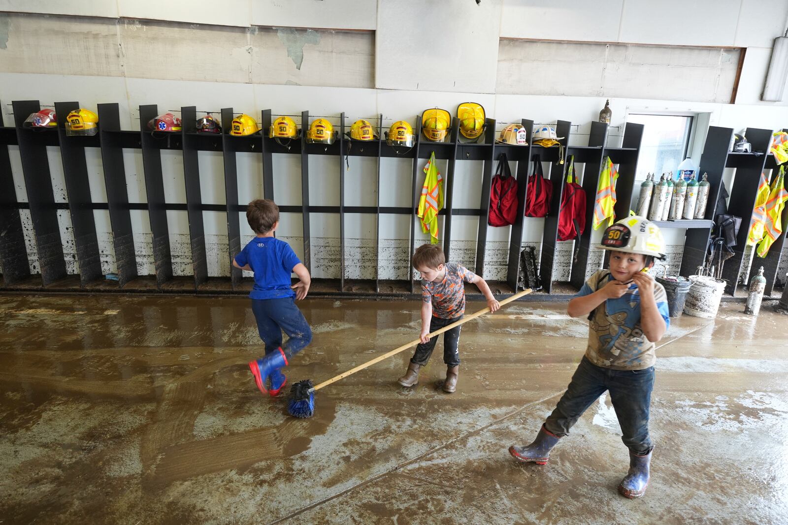 Children help clean up the fire station after flooding on Wednesday, May 14, 2025 in Westernport, Md. (AP Photo/Gene J. Puskar)