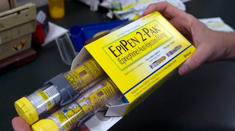 FILE - In this July 8, 2016, file photo, a pharmacist holds a package of EpiPens epinephrine auto-injector, a Mylan product, in Sacramento, Calif. Mylan has started selling a generic version of its emergency allergy treatment EpiPen at half the price of the branded option, the cost of which drew national scorn and attracted Congressional inquiries. (AP Photo/Rich Pedroncelli, File)