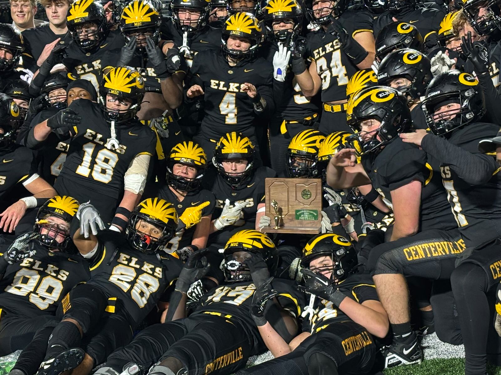 Trophy Centerville football players pose with OHSAA football regional championship trophy after beating Wayne at Welcome Stadium on Friday night, Nov. 22, 2024.
