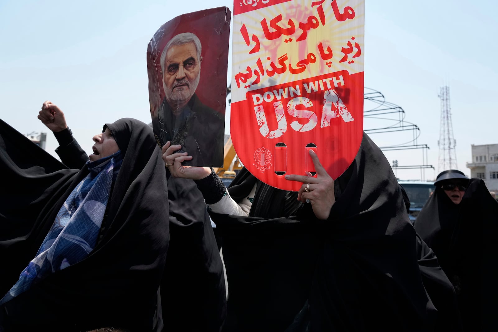 An Iranian protester holds up an anti-U.S. placard and a poster of the late revolutionary guard Gen. Qassem Soleimani, who was killed in a U.S. attack in Iraq in 2020, in an anti-Israeli gathering in Tehran, Iran, Friday, June 13, 2025. (AP Photo/Vahid Salemi)