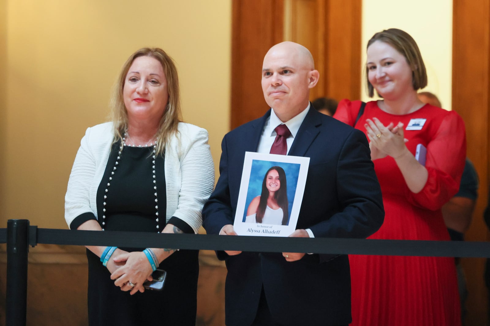 Ilan Alhadeff holds a photograph of his daughter Alyssa Alhadeff, next to his wife Lori, as they are recognized by Gov. Brian Kemp (not pictured) before Kemp signs the student safety bill, House Bill 268, at the north wing steps of the Georgia State Capitol, Monday, April 28, 2025, in Atlanta. (Jason Getz/Atlanta Journal-Constitution via AP, Pool)