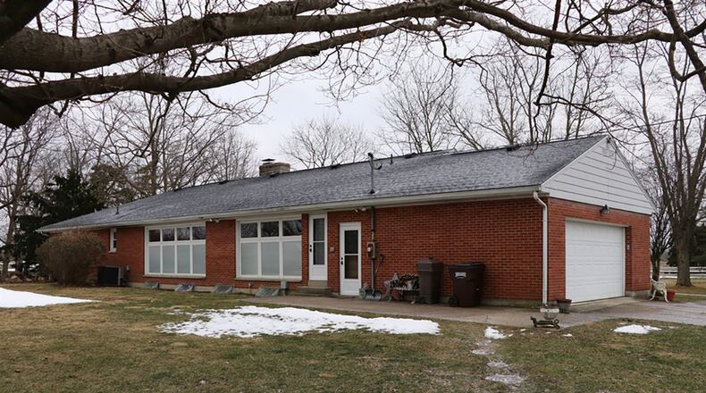 At the back of the house, natural refinished hardwood floors fill the formal dining room and living room. The dining room has a single door that opens to the back yard, and both rooms have floor-to-ceiling windows.