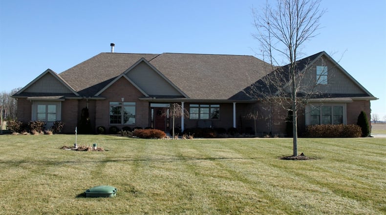 A long driveway extends toward this brick, 1.5-story home in Ludlow Falls. Recessed at the center of the home the long front porch is sheltered from the elements. Professionally landscaped flower beds are planted with dwarf trees, ornamental grasses, boxwoods and evergreens. CONTRIBUTED PHOTOS BY KATHY TYLER