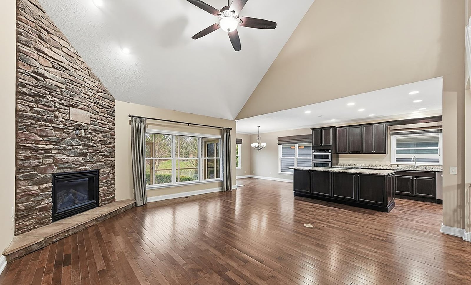 The open concept kitchen and family room has hardwood floors throughout. The family room has a vaulted ceiling, ceiling fan, recessed lighting, and a stone floor to ceiling fireplace. The kitchen has an eat in area and an exterior door opening to the covered back screened in patio. CONTRIBUTED