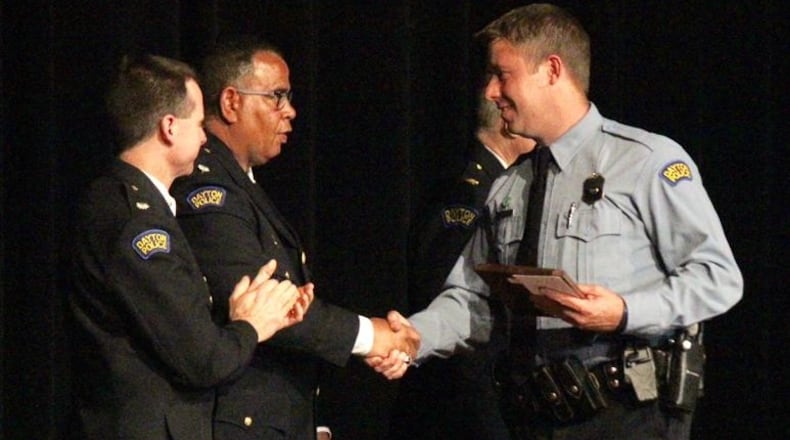 Dayton police officer Jason Olson, right, recipient of the Steve Whalen Memorial Policing Award, shakes hands with Lt. Col. Mark Ecton. CHUCK HAMLIN / STAFF