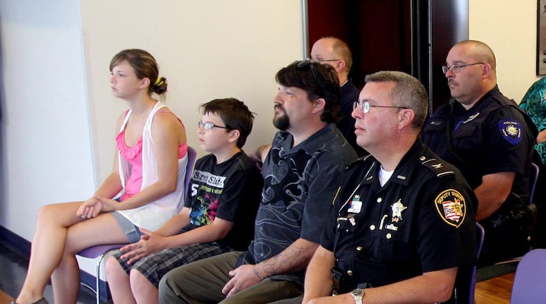 Matthew Hopper, the husband of fallen Clark County Deputy Suzanne Hopper, and his children, Madeline and Cole Hopper, sit in the front row with Clark County Chief Deputy David Rapp during the dedication of a new firearms training simulator (FATS) in Suzanne Hopper's memory at the Dayton campus of Kaplan College Saturday, June 11, 2011. E.L. Hubbard photography