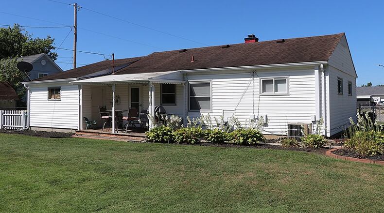 A door from the kitchen opens to a covered wooden deck in the fenced rear yard.