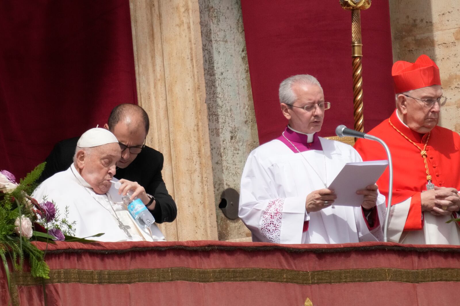 Pope Francis, left, sips water as he appears at the central lodge of St. Peter's Basilica to bestow the Urbi et Orbi (Latin for to the city and to the world) blessing at the end of the Easter mass presided over by Cardinal Angelo Comastri in St. Peter's Square at the Vatican Sunday, April 20, 2025. (AP Photo/Gregorio Borgia)