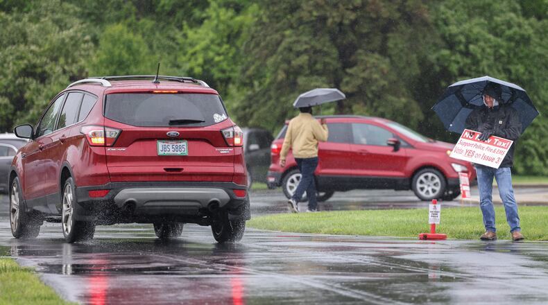 Huber Heights City Manager John Russell holds a sign in support of a renewal levy for city police, fire and emergency services as voters head to the polls on Tuesday at New Season Ministry in Huber Heights. Russell, who formerly worked as a firefighter, didn't let rainy conditions stop him from showing support for the levy. BRYANT BILLING / STAFF
