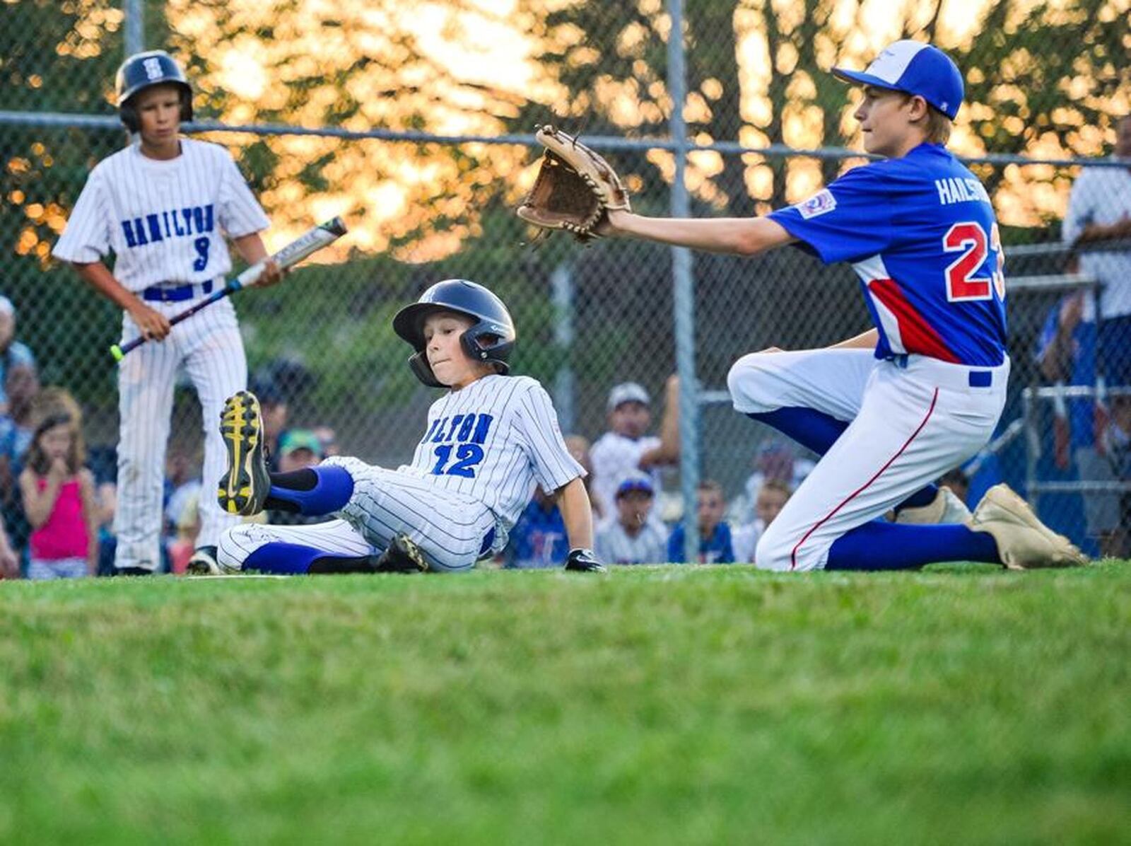 Hamilton West Side’s Eddie Tanner scores on a wild pitch in front of Hamilton-Fairfield pitcher Braylin Hailstones during Thursday night’s Little League District 9 championship game at West Side. The hosts won 15-0. NICK GRAHAM/STAFF