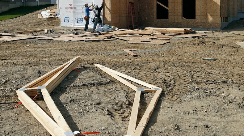 Local home builders are enjoying a resurgence, hitting their highest number of permits pulled in a decade. This photo from November 2016 shows carpenters Jacob Scoby, left, and Leroy Gillem wrap a home on Freedom Point in the Hunter’s Ridge development in Beavercreek. TY GREENLEES / STAFF