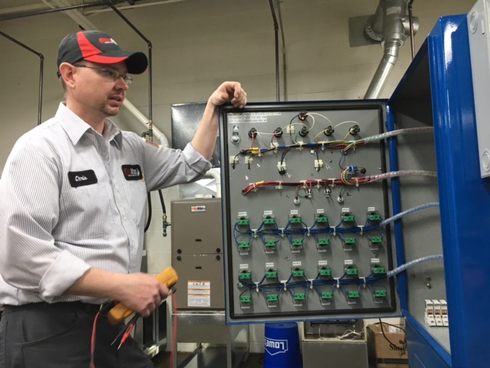 Chris Bryant, a longtime McAfee Heating and Air employee and instructor, explains an electrical trainer machine in the company’s Kettering distribution and training facility. THOMAS GNAU/STAFF
