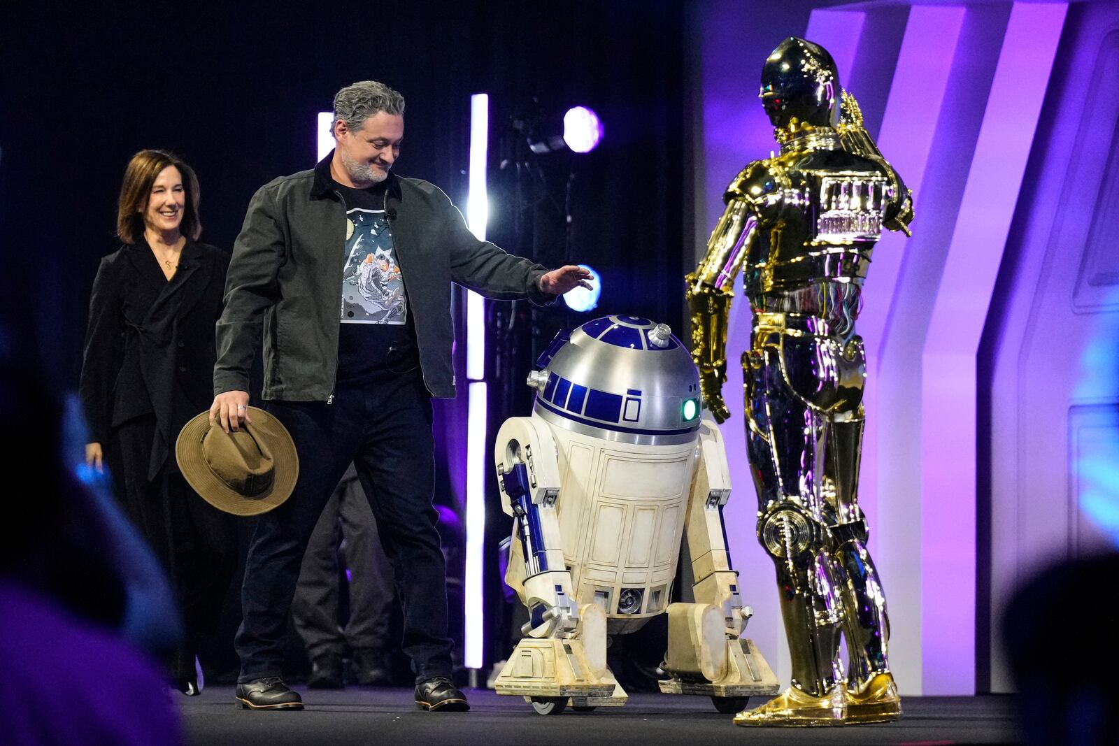 Film producer Kathleen Kennedy, left, and director Dave Filoni are welcomed by R2-D2 and C-3PO, right, as they appear on stage during a fan convention called the Star Wars Celebration in Chiba, near Tokyo, Friday, April 18, 2025. (AP Photo/Hiro Komae)