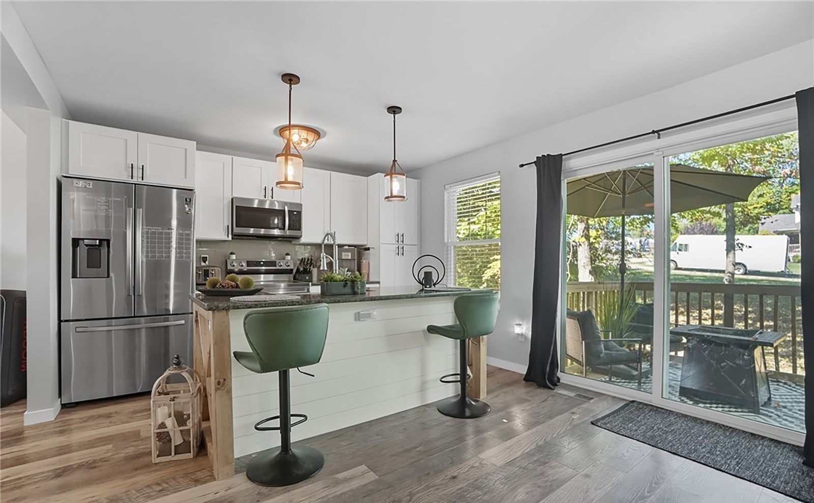 The kitchen has wood cabinets and an island with bar seating. It has LVP flooring and sliding glass doors open to the back yard deck and wooded lot. CONTRIBUTED