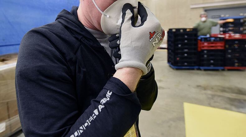 Capt. Nathan Snow of the National Air and Space Intelligence Center, checks his mask before stocking shelves as a volunteer at the commissary on Wright-Patterson Air Force Base April 9. (U.S. Air Force photo/Ty Greenlees)