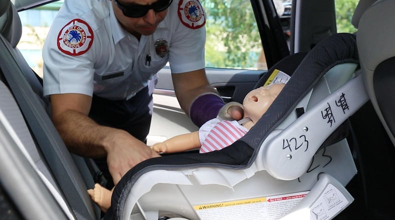A City of Miami Fire Rescue member removes a test dummy used for a rescue demonstration on the methods to save the life of an infant or pet in case of emergency, during a news conference at the Florida Highway Patrol headquarters in Doral, Fla., on June 22. (Sebastian Ballestas/Miami Herald/TNS)