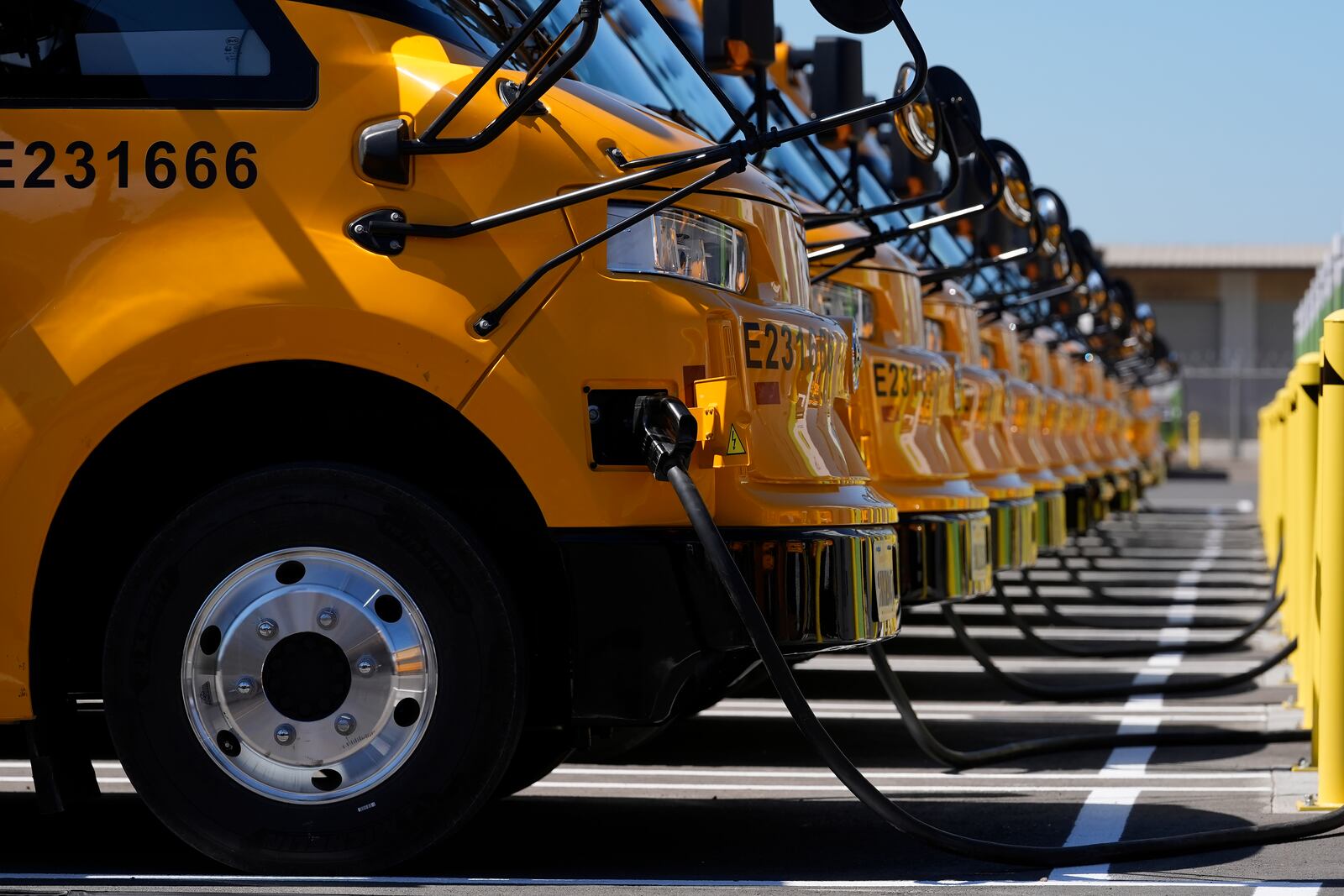 FILE - Zum electric buses are plugged into charging a station before a news conference announcing the Oakland Unified School District as being the first major school district in the country to use 100% electric school buses at the Zum/OUSD bus yard in Oakland, Calif., on Aug. 27, 2024. (AP Photo/Jeff Chiu, File)
