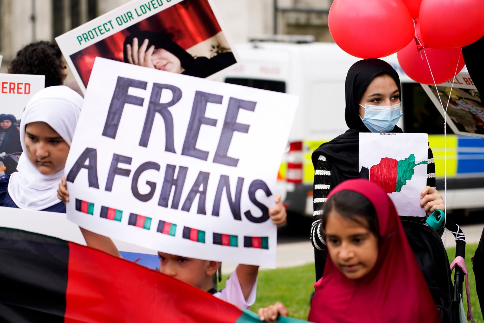 FILE - Demonstrators hold placards, during a protest in Parliament Square, London, Aug. 18, 2021. (AP Photo/Alberto Pezzali, file)