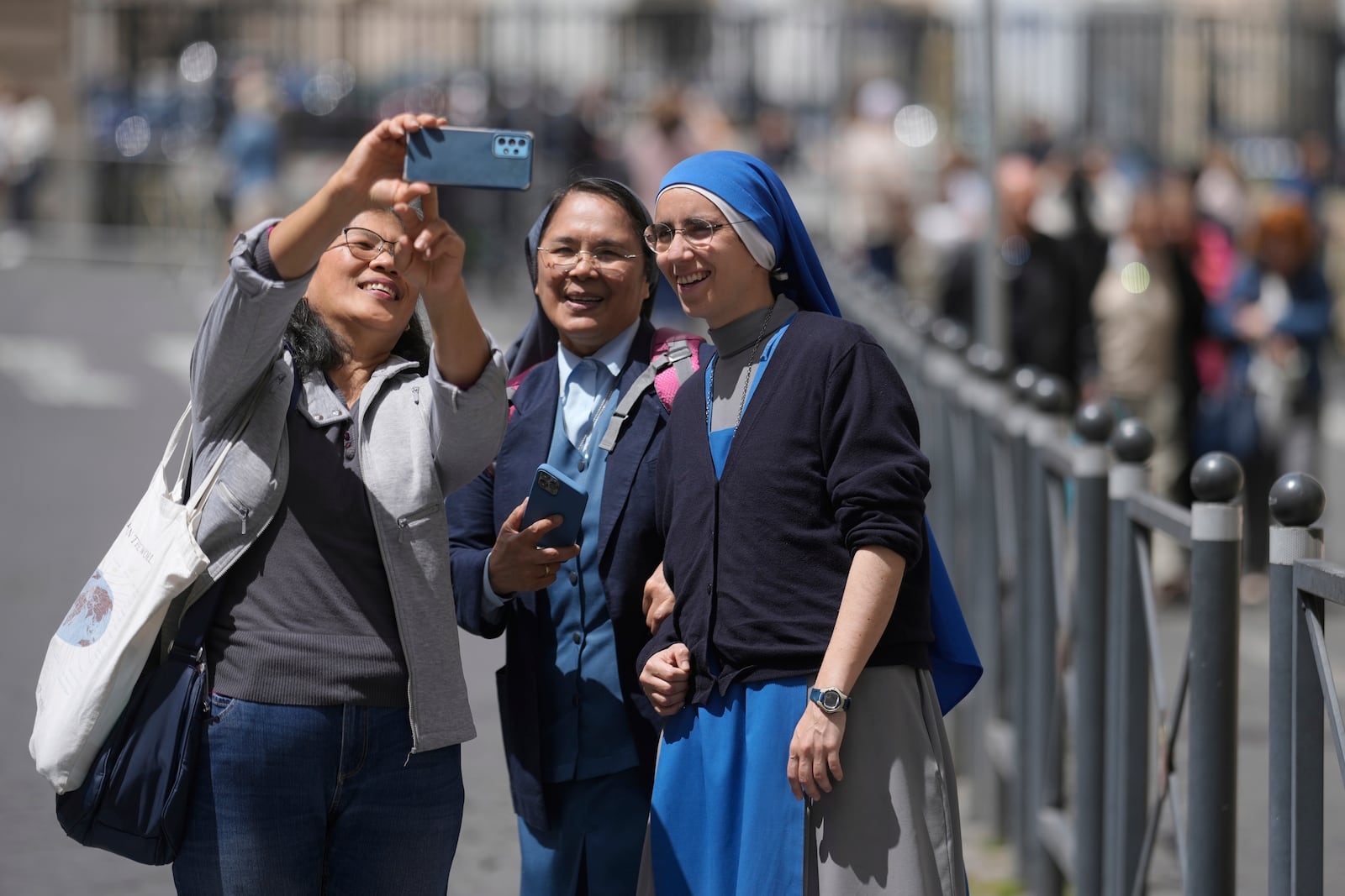 A woman takes selfie with nuns at St. Peter's Square where 133 cardinals are gathering on the second day of the conclave to elect successor of late Pope Francis, at the Vatican, Thursday, May 8, 2025. (AP Photo/Markus Schreiber)