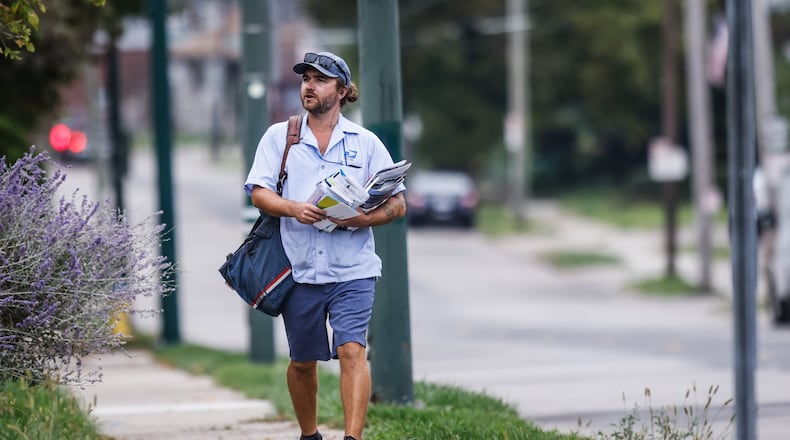 A mail carrier delivers mail on Watervliet Ave. Monday Oct. 4, 2021.  The mail may soon cost more and take long to arrive under postmasters 10-year plan. JIM NOELKER/STAFF